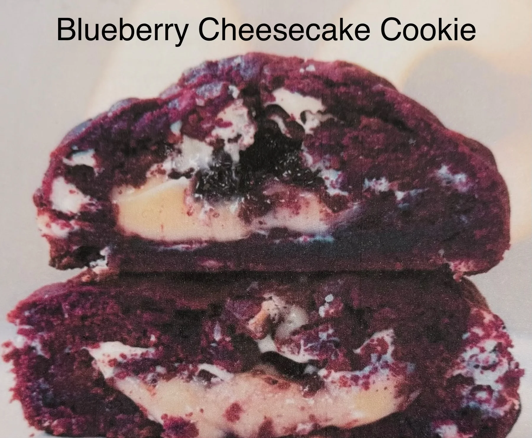 Blueberry cheesecake cookie broken open to show its berry and cheesecake filling.