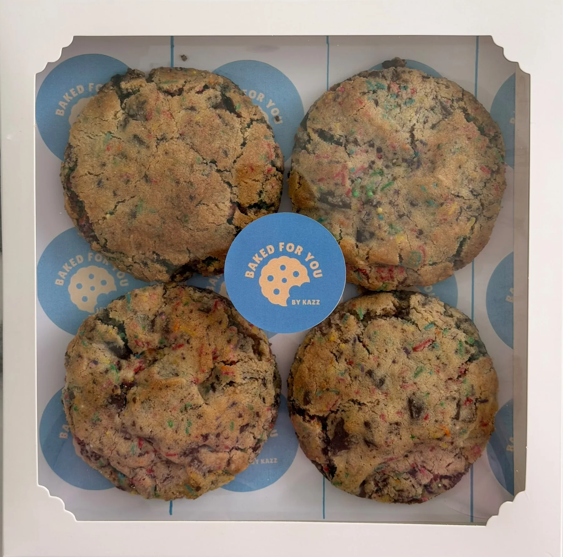 A Baked For You by Kazz branded box of colourful sprinkle cookies.