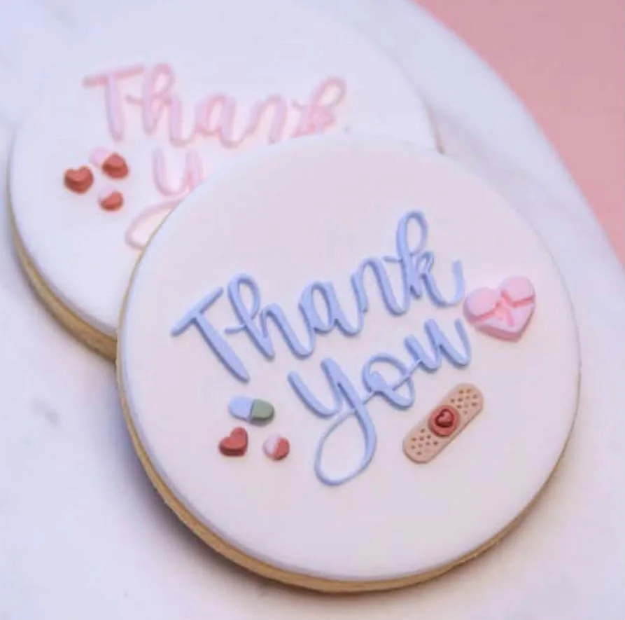 Two white iced thank-you cookies with soft pastel details.